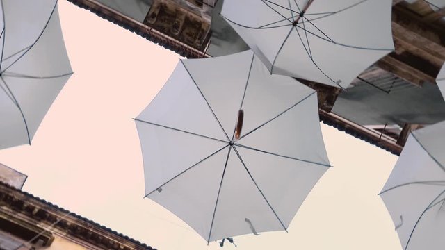 White umbrellas are hanging on the rope between buildings