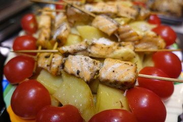 Salmon skewers on a plate with red tomatoes