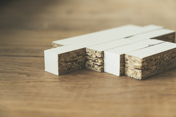 Small white textured chipboard pieces arranged on the wooden floor close up
