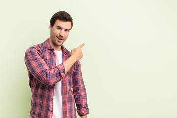  looking excited and surprised pointing to the side and upwards to copy space
