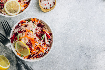 Spring healthy vegan salad with raw beet, carrot and cabbage in white bowls. Alkaline Diet concept. Top view. Flat lay