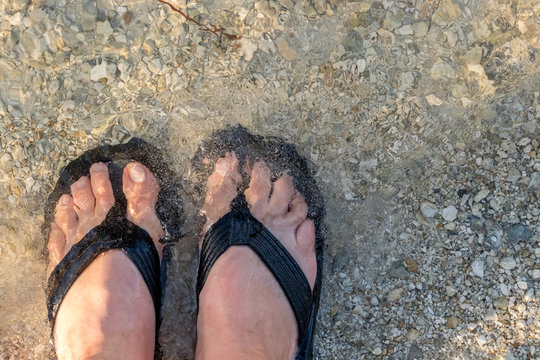 flip flops and toes in the water at the beach