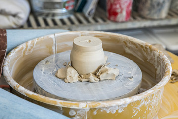 an unfinished pot bowl upside down on a pottery wheel being trimmed and shaped