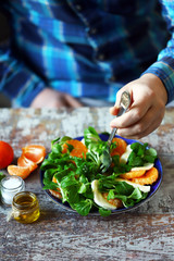 Chef preparing a healthy salad. Male hand mixed salad with mozzarella and tangerine. Salad a la caprese with corn salad and mandarin.
