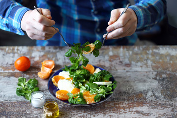 Chef preparing a healthy salad. Male hand mixed salad with mozzarella and tangerine. Salad a la caprese with corn salad and mandarin.