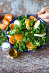 Chef preparing a healthy salad. Male hand mixed salad with mozzarella and tangerine. Salad a la caprese with corn salad and mandarin.