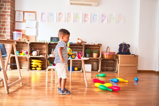 Beautiful toddler boy playing bowling at kindergarten