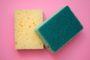 New foam sponges for washing dishes. Green and yellow sponge top view. Bilateral foam sponges on a pink background.