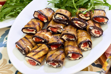 Rolls of fried eggplant with mayonnaise garlic sauce and tomato, close-up