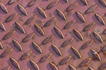 Iron corrugated plate of red color with small rust areas. Technological background with texture for the design of industrial surfaces. An element of iron construction. Antiskid surface