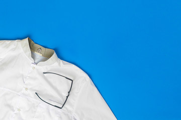 simple classic white doctor uniform clothes and eyeglasses flat lay on the table