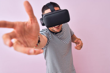 Young man playing video game wearing virtual reality glasses, looking at virtual simulation amazed and smiling happy