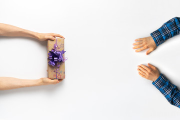 top view, two perople giving a beautiful present box with a color ribbon on the surface