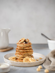 stack of oatmeal banana pancakes with date syrup and nuts. healthy food concept. gray background, vertical image