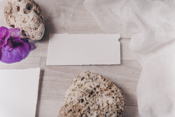 Wedding invitation mockup with orchid, papers on white textile background. Top view, flat lay. Wedding stationary. Perfect for presentation of your invitation, menu, greeting cards