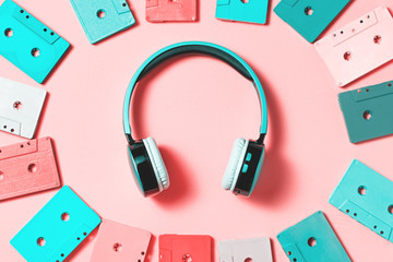 Painted audio cassettes in bright colors and blue earphones on pastel background, copy space, top...