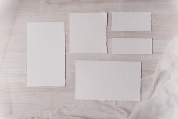 Wedding invitation mockup with paper, stone, green branch on white textile background. Top view, flat lay. Wedding stationary. Perfect for presentation of your wedding invitation, menu, greeting cards