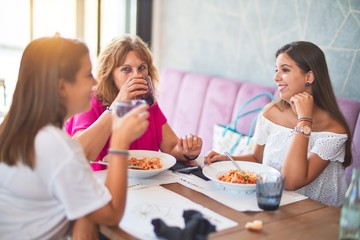 Beautiful group of women sitting at restaurant eating food speaking and smiling