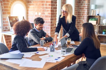 Group of business workers smiling happy and confident. Working together with smile on face. Middle age beautiful woman standing explaining documents at the office