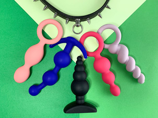 Sex toys. Five butt plags and collar on a green background . Useful for adult, sex shop