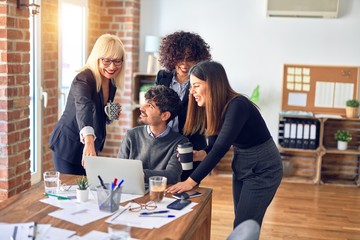Fototapeta premium Group of business workers smiling happy and confident. Working together with smile on face using laptop at the office