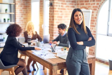 Group of business workers working together. Young beautiful woman standing smiling happy looking at the camera at the office