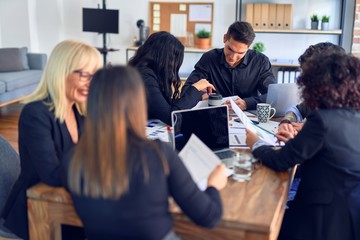 Group of business workers smiling happy and confident. Working together with smile on face  using laptop and speaking at the office
