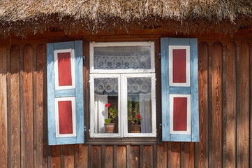 Old wooden peasant thatched farmhouse with decorative shutters