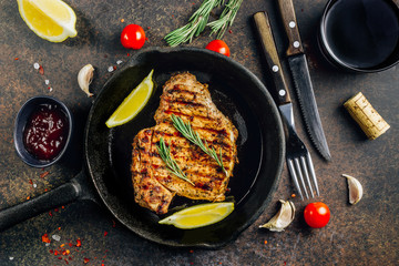 Roasted pork steak in frying pan over dark background. Top view.