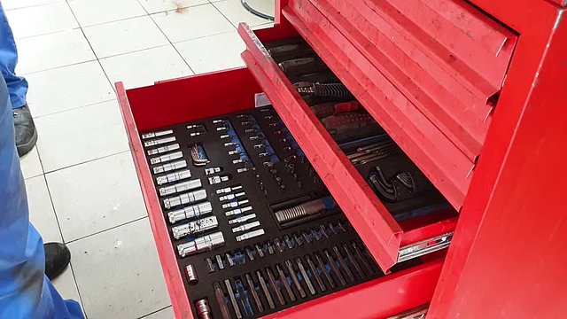 the mechanic opens a red metal box and puts there tools