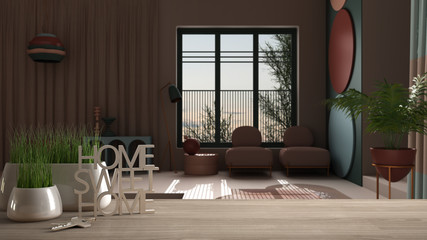 Wooden table, desk or shelf with potted grass plant, house keys and 3D letters making the words home sweet home, over colored living room with window, interior design, blur background