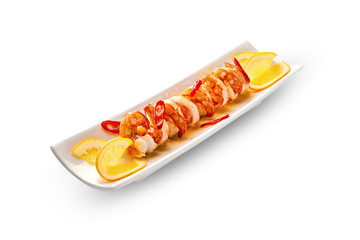 Fried king prawns in a plate with sauce and oranges, with red hot pepper, closeup. White plate on an isolated background.