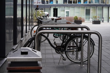 Fototapeta na wymiar One old bike is fixed to a metal structure for Parking bicycles or scooters, environmental transport in the city. Moving by bike every day. bicycle at street parking outdoors