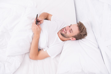 Set up morning alarm. Apps that help monitor sleep. Man use mobile phone in bed. Waking up. Application analyzes stages of sleep and wakes you up at optimal time. Provide deeper sleep analysis