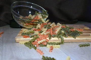 Multi-colored pasta on a wooden board. Food.