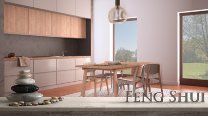 Wooden vintage table shelf with pebble balance and 3d letters making the word feng shui over cosy gray and wooden kitchen with dining table and chairs, zen concept interior design