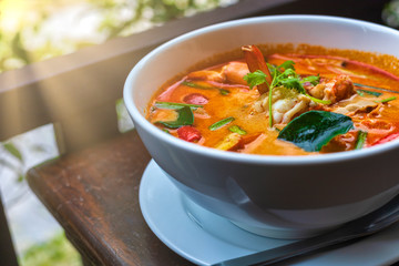 Tom Yam kung Spicy Thai soup with shrimp in white bowl on wood table. With copy space for text or design.