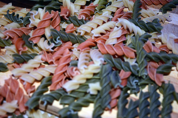 Multi-colored pasta on a wooden board. Food.