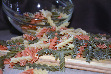 Multi-colored pasta on a wooden board. Food.
