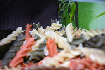 Multi-colored pasta on a wooden board. Food.