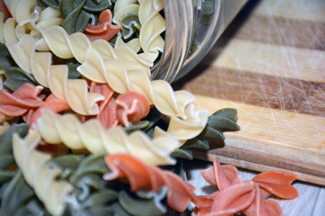 Multi-colored pasta on a wooden board. Food.