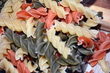 Multi-colored pasta on a wooden board. Food.