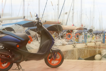 Scooter stands on the dock on the background of sailing cruise yachts in the Mediterranean marina....
