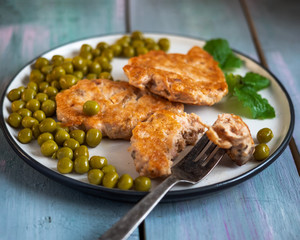Breakfast of chum salmon cutlets with green peas and a fork