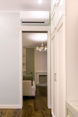 View of the air conditioning above the door in the room. Living room with fireplace behind the door