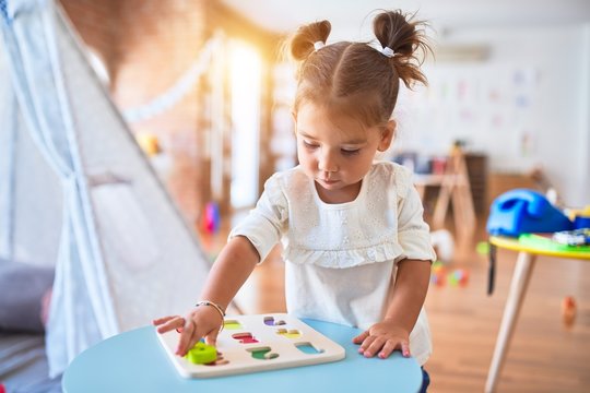 Young beautiful toddler learning mathematics playing with maths game at kindergaten