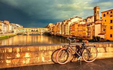 Foto op Plexiglas Uitzicht op de middeleeuwse stenen brug Ponte Vecchio over de rivier de Arno en vintage fiets in Florence, Toscane, Italië. Florence stadsgezicht. De architectuur en het oriëntatiepunt van Florence. © Vladimir Sazonov