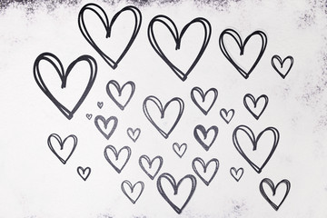 Texture of drawn hearts in black on a white background from flour. Valentine's Day.