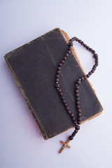 Old holy bible and rosary necklace. White isolated background.