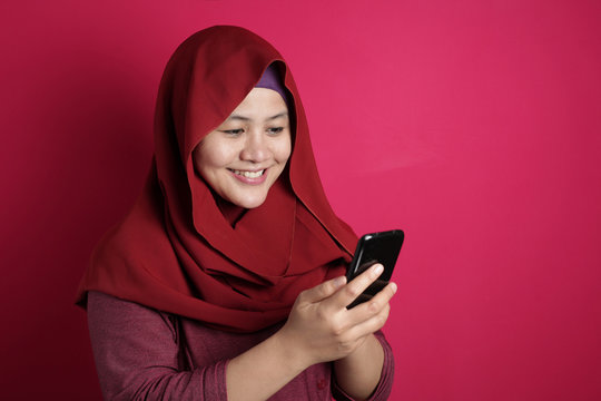 Muslim Woman Smiling While Reading Message on Smart Phone